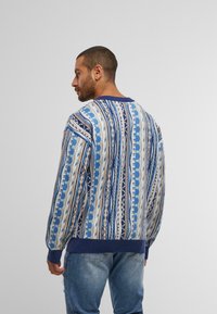 Gebreide trui in tinten blauw, met een geometrisch patroon van horizontale lijnen en accenten. Ribgebreide manchetten en zoom.