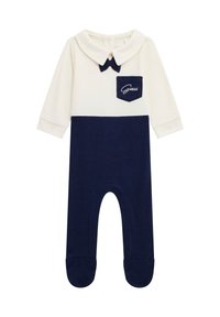 Combinaison en coton avec un haut blanc, un bas bleu marine, un col pointu, un accent nœud et une petite poche bleu marine avec broderie "Guess". Design à pieds.