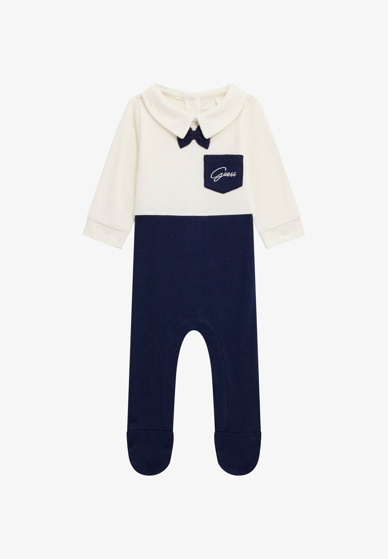 Combinaison en coton avec un haut blanc, un bas bleu marine, un col pointu, un accent nœud et une petite poche bleu marine avec broderie "Guess". Design à pieds.