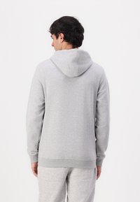 Light gray hoodie made of soft fabric featuring a large, adjustable hood, long sleeves, and ribbed cuffs. Simple design without patterns.