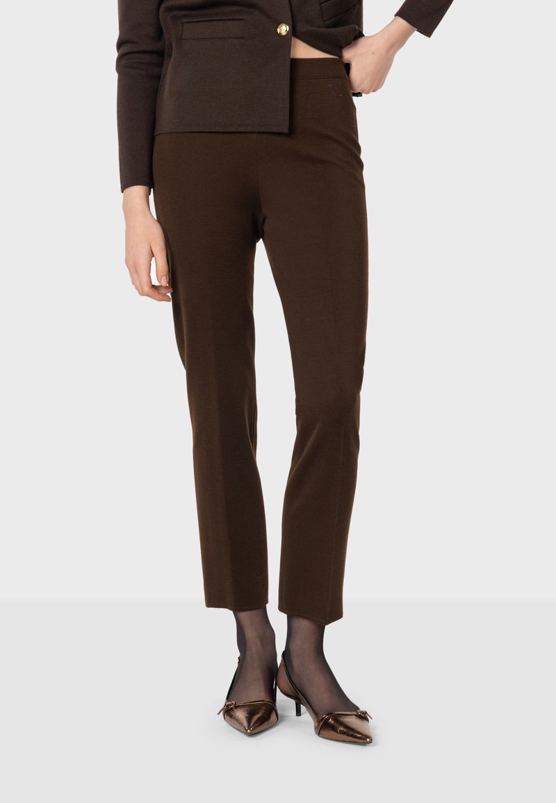 Bruna skräddarsydda byxor med en figurnära passform, mjuk textur och slät yta, kombinerade med bronsfärgade slingback-klackar.