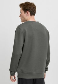 Dunkelgrauer Sweatshirt aus glattem Stoff, mit langen Ärmeln, rundem Halsausschnitt und gerippten Bündchen und Saum. Keine sichtbare Markenkennzeichnung.