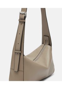 Borsa a spalla in pelle beige con forma triangolare, tracolla regolabile e dettagli in zip argentati. Texture liscia e design minimalista.