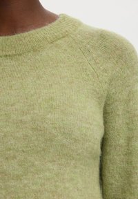 Hellgrüner Pullover mit rundem Ausschnitt, aus weichem, flauschigem Material. Mit Raglanärmeln und einer strukturierten Oberflächenstruktur.