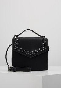 Czarna torebka o usztywnionym kształcie, wyposażona w górną rączkę, regulowany pasek oraz srebrne ćwieki ułożone w wzór jodełki.