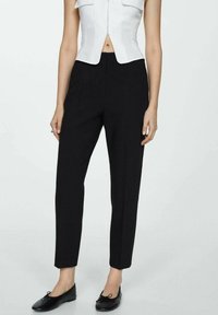 Pantalones negros ajustados con un corte slim, cintura alta y bolsillos. Fabricados en una tela suave con un diseño de pierna recta. Acentuados con pliegues sutiles.