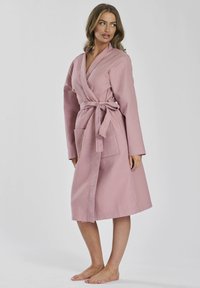 Accappatoio rosa con motivo a waffle, maniche lunghe, vita con cintura e tasche laterali, realizzato in tessuto morbido, design lungo fino al ginocchio.