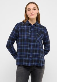 Zila un melna pleda krekls ar garām piedurknēm, pogu priekšpusi, smailu apkakli un krūšu kabatu. Audums ir mīksts un strukturēts.