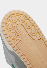 Světlohnědá gumová podrážka tenisky Adidas s kruhovými vzory podrážky, logem Adidas a texturovanými gripovými liniemi.