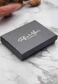 Grau strukturierte Schmuckschatulle mit einem silbernen Logo auf dem Deckel, ausgestattet mit einer schlanken rechteckigen Form und klaren Kanten.