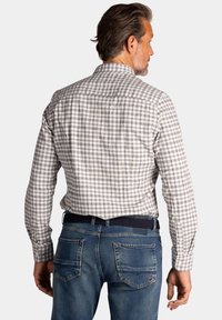 Heren geruit overhemd in wit, grijs en lichtblauw, met een kraag, knoopsluiting aan de voorkant en lange mouwen, gecombineerd met blauwe denim jeans.