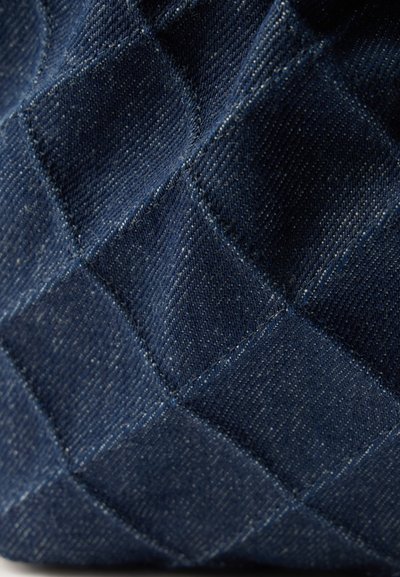 Σκούρο μπλε υφασμάτινο καπιτονέ με ραφή σε τετράγωνα και υφή ύφανσης, δημιουργώντας ένα τρισδιάστατο εφέ.