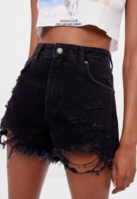 Shorts en denim noir taille haute avec un ourlet effiloché et des détails usés. Comprend une fermeture à bouton argenté et une texture délavée.