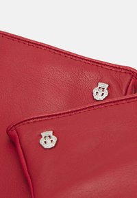 Portafoglio in pelle rossa con hardware argentato, dettagli di cucitura visibili e una superficie texture. Due bottoni decorativi sono posizionati in modo prominente.