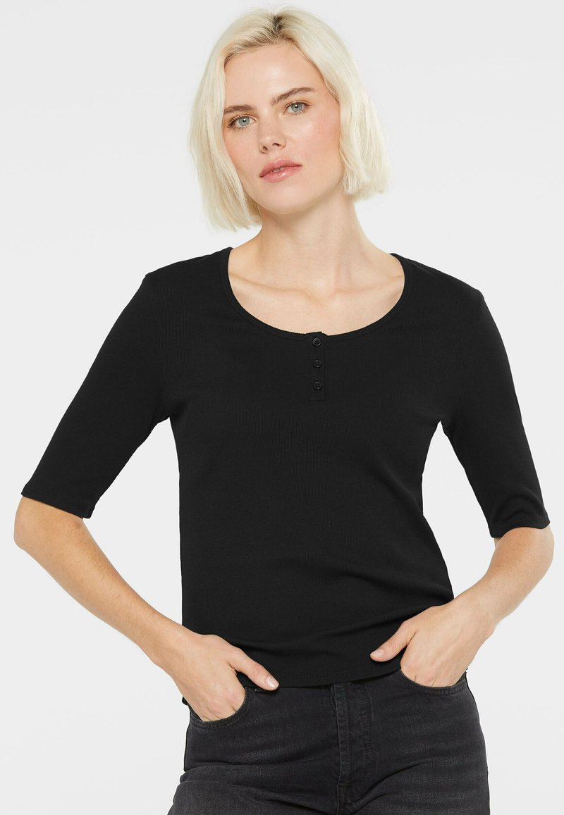 Schwarzes Kurzarmoberteil mit rundem Halsausschnitt, das auf der Vorderseite eine Knopfleiste hat. Hergestellt aus einem glatten, enganliegenden Stoff.