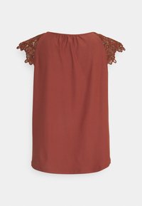 Haut sans manches rouge rouille avec manches courtes en dentelle crochetée, détail froncé à l'encolure dos, dos uni, présenté sur fond blanc.