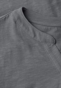 T-shirt gris avec un col rond, doté d'une texture subtile, d'un tissu doux et de coutures plates pour une finition lisse.