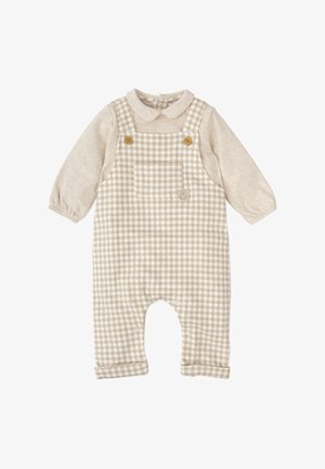 Salopette à carreaux beige avec une chemise à manches longues beige clair. Elle dispose de boutons en bois, d'une poche poitrine et de fermetures à pression aux jambes.