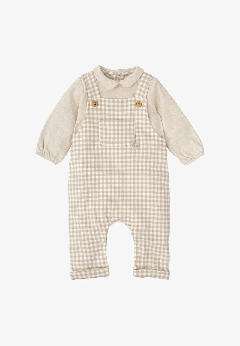 Peto a cuadros beige con una camisa de manga larga beige claro. Cuenta con botones de madera, un bolsillo en el pecho y cierres a presión en las piernas.