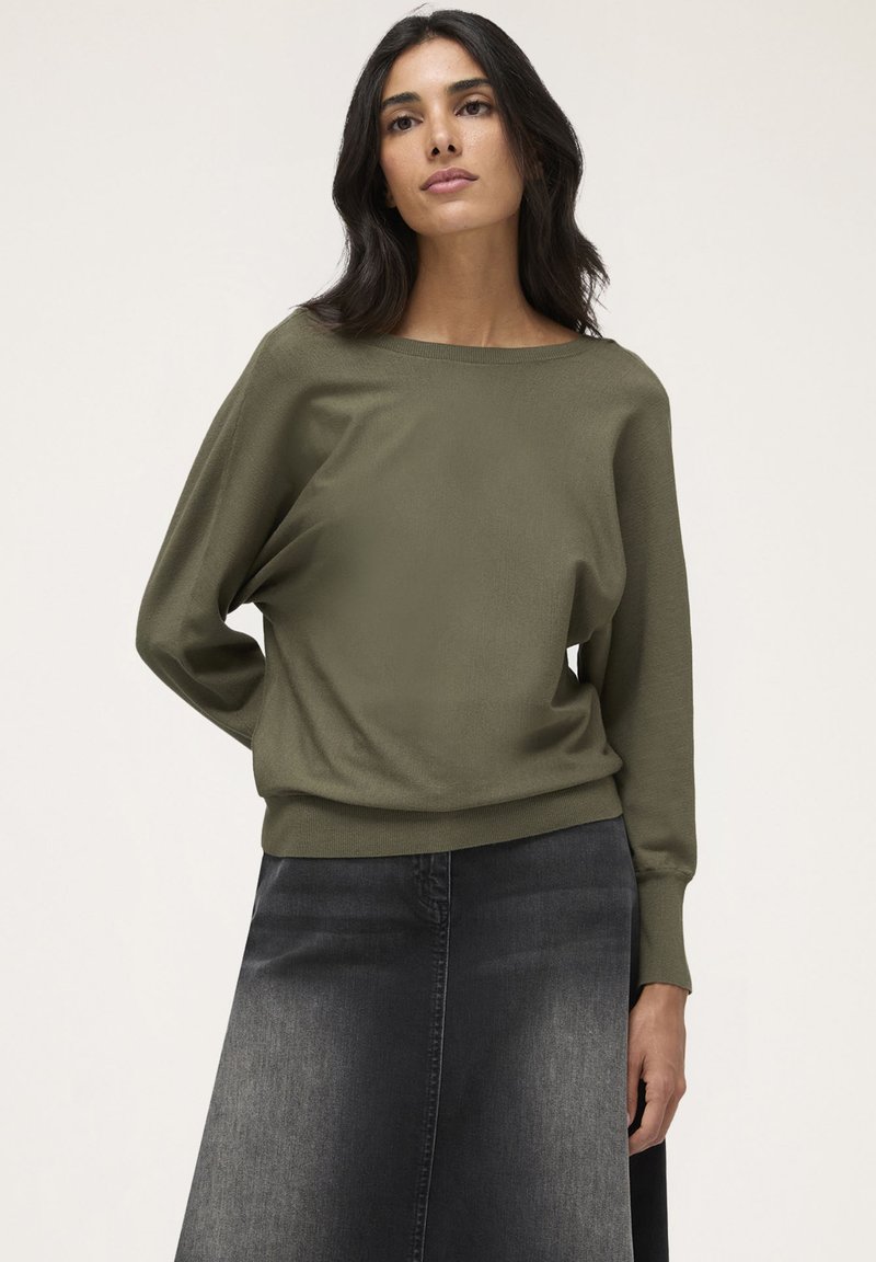 Pulover ușor, de culoare verde măsliniu, cu mâneci lungi și un decolteu larg, asortat cu o fustă A-line din denim închis. Textură netedă și moale.