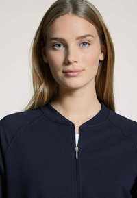 Marine blauwe rits sweatshirt met een ronde kraag, geribde manchetten en een textielstructuur. Voorzien van een centrale rits en een zachte stof.