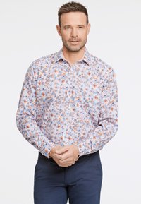 Chemise à manches longues dans des couleurs pastel claires, avec un motif floral agrémenté de détails oranges et bleus. Design à boutons, tissu doux, col classique.