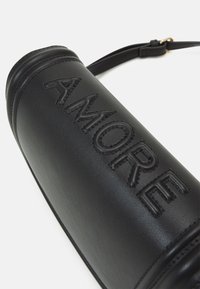 Czarna skórzana torba na ramię z wytłoczonym napisem "AMORE", cylindryczny kształt i regulowany pasek. Gładka tekstura z subtelnymi detalami szycia.