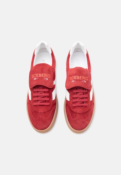Paire de baskets en daim rouge avec des bandes latérales blanches, des lacets rouges, des semelles en gomme, et « ICEBERG 1974 » imprimé sur les languettes.