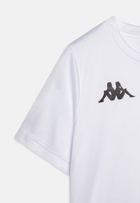 Bijela majica kratkih rukava od glatkog materijala, s crnim uskim logotipom dvije sjedeće figure na gornjem lijevom dijelu prsnog koša.