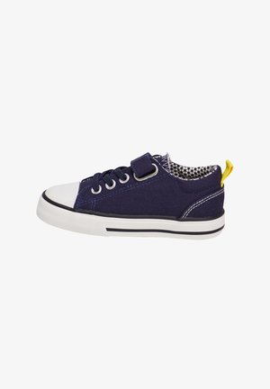 Sneaker in tela blu navy con punta e suola in gomma bianca, suola a strisce nere e bianche in contrasto e anello giallo sul tallone. Cinturino regolabile in velcro.