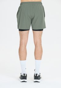 Heren sportshorts in olijfgroen, met een elastische tailleband, lichtgewicht stof en een gelaagd ontwerp over zwarte binnenbroeken.