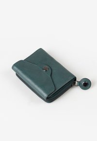 Teal leather wallet with a snap closure, zippered edge, and a circular hardware accent. Compact, with a smooth texture and simple design.