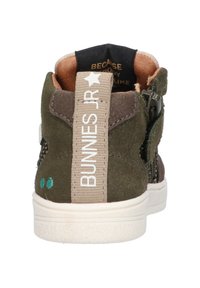 Groene suède sneakers met een witte rubberen zool, bruine accenten en een beige stoffen trekhaak met de label "BUNNIES JR" in het wit. Bevat juist zijpanelen van gaas.