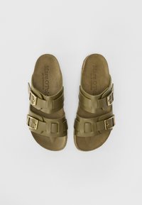 Oliven grønne sutsko med to justerbare stropper, guld spænder og en tekstureret indersål. Robust gummisål og minimalistisk design.