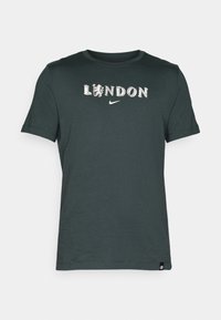 Tumši zaļš kokvilnas T-krekls ar uzrakstu "LONDON" un lauva grafiku, ar Nike simbolu. īsas piedurknes un apaļa dekoltē forma.