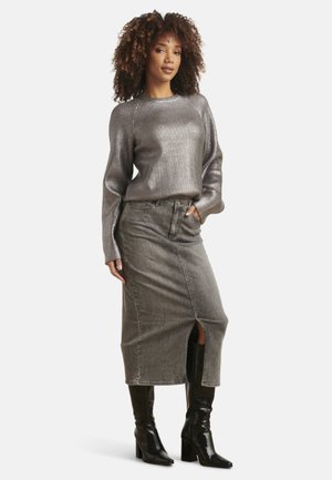 Metallic silver ribbed sweater paired with a knee-length gray denim skirt featuring a front slit. Model wearing knee-high black boots.
