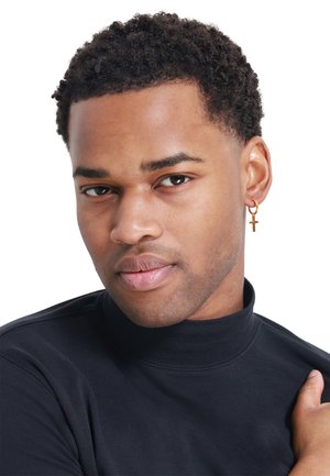 Haut à col roulé noir, texture lisse ; modèle porte une boucle d'oreille en croix dorée. Cheveux courts et bouclés, teint neutre. Gros plan.