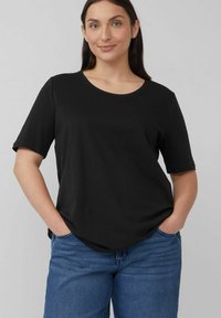 Black short-sleeve t-shirt with a scoop neckline, featuring a relaxed fit and soft, smooth fabric. Worn with blue denim jeans.