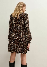 Vestido con estampado de leopardo que presenta un diseño en capas, mangas largas y una cintura ajustada. Está hecho de un tejido ligero con una textura suave.