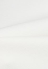Nahaufnahme von glattem, weißem Stoff mit sanften Falten und feiner Textur, die bei gleichmäßiger Beleuchtung sichtbar ist.