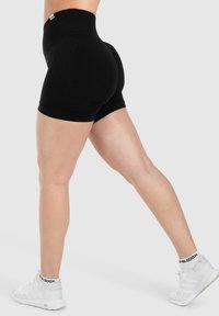 Pantaloni corti neri a vita alta in un tessuto elastico con un design aderente. Presentano una superficie liscia e dettagli di cucitura discreti.
