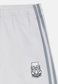 Light gray athletic shorts with an elastic waistband, featuring gray side stripes and a white embroidered logo on the left thigh.