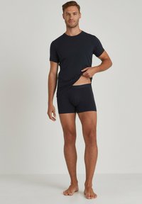 Maglietta a maniche corte blu scuro e boxer, entrambi in un tessuto morbido ed elastico. I boxer presentano un motivo discreto sulla vita.