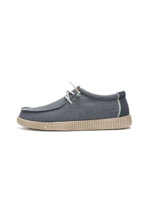 Zapato casual de corte bajo con tejido texturizado en azul marino, suela de goma beige, cordones gris claro y detalles mínimos de costura mostrado en perfil lateral.