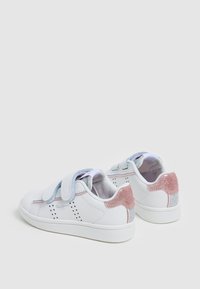 Sneaker bianchi con strappi a velcro, caratterizzati da un accento scintillante in rosa e argento sul tallone, piccole perforazioni a forma di stella e una superficie testurizzata.
