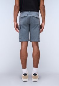 Gray cargo shorts with side and back pockets, featuring a relaxed fit. Worn with white socks and light-colored sneakers.