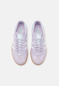Baskets en cuir lilas avec des rayures blanches, un embout texturé et des accents bleu clair. Elles présentent une semelle en caoutchouc naturel et un design de lacets assorti.