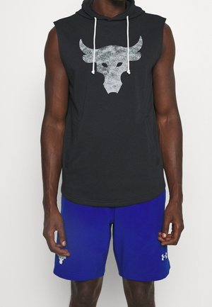 Sweat à capuche noir sans manches avec logo de taureau blanc et cordons, porté avec un short de sport bleu vif avec logo blanc Under Armour.