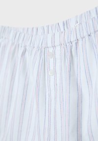 Tissu blanc avec de fines rayures verticales rouges et bleues, doté d'une ceinture élastique et de deux boutons blancs à l'avant.