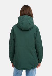 Giacca impermeabile verde con cappuccio, caratterizzata da una texture liscia, polsini elastici e un orlo curvo, vista da dietro.